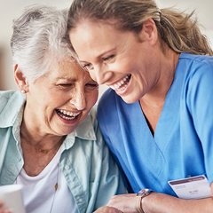 Caregiver and older woman laughing together