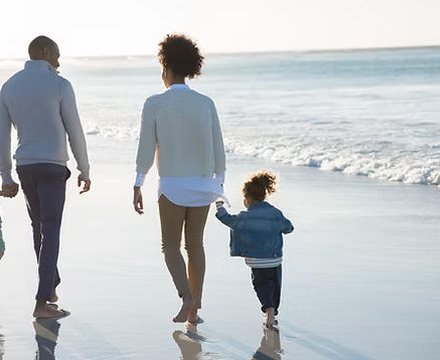 Family walking along the shore at sunrise