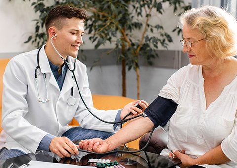 Doctor measuring an older woman's blood pressure at home