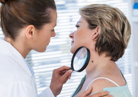 Skin specialist checking a woman's neck with a magnifier