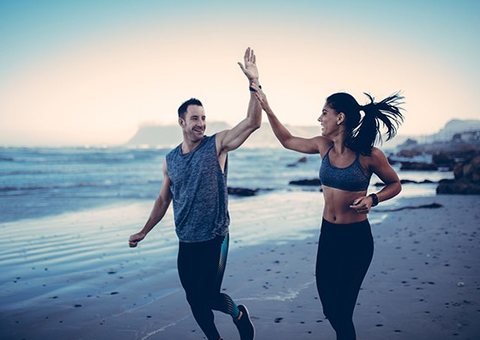 Couple celebrating a beach run with a high five
